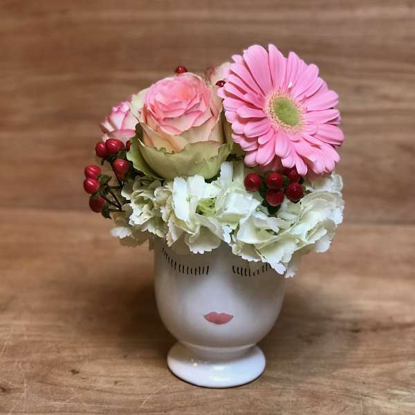 Pink gerbera and rose arrangement in a face-shaped vase
