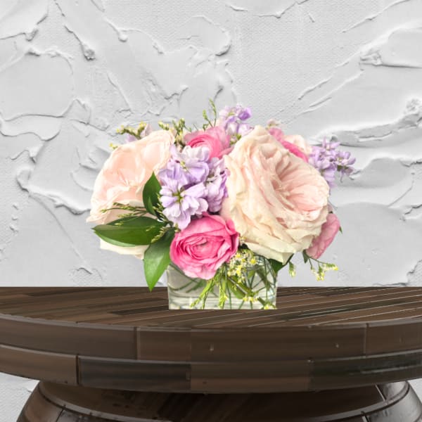 Pink and cream roses with lavender flowers in a glass vase