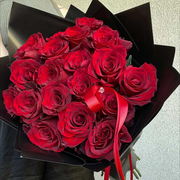 Bouquet of red roses wrapped in black paper with a red ribbon