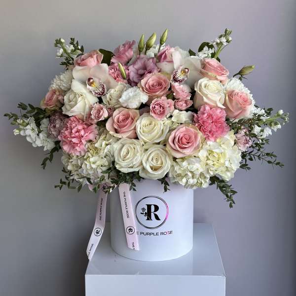 Large pink and white rose and hydrangea arrangement in a white hatbox with logo ribbon