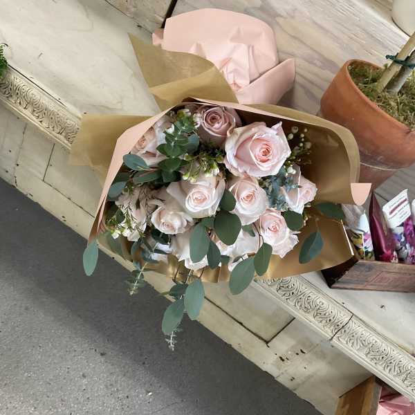 Bouquet of pale pink roses wrapped in tan and blush paper
