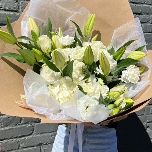 Large bouquet of white lilies and carnations wrapped in kraft paper