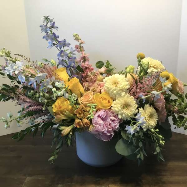 Mixed bouquet in a gray vase with yellow, pink, and blue flowers