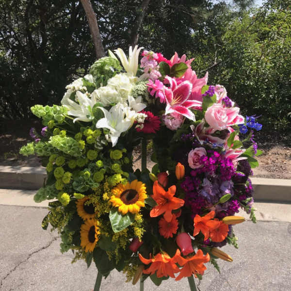 Large standing floral spray with lilies, roses, and sunflowers