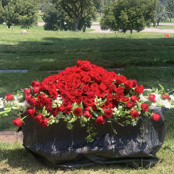 Large red rose arrangement in a black container on grass