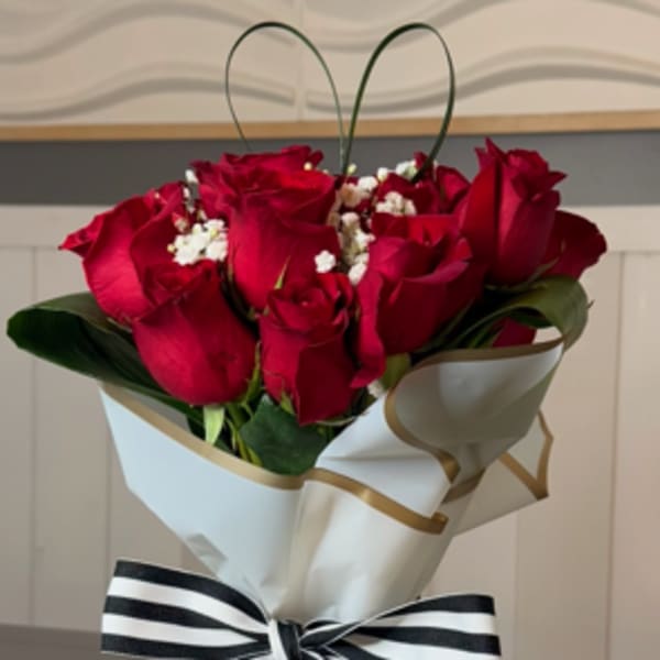 Bouquet of red roses wrapped in white paper with a striped ribbon
