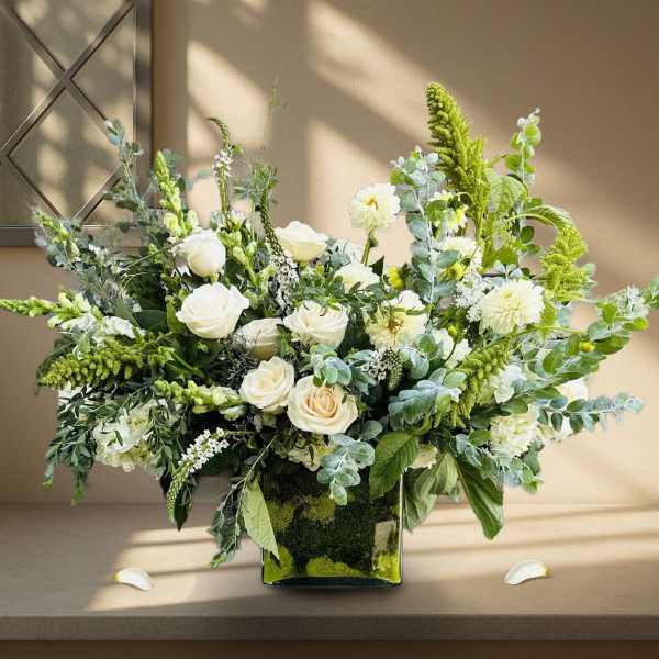 White roses and green blooms in a square glass vase