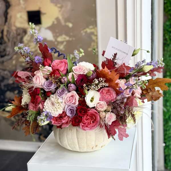 Mixed pink and purple flower arrangement in a white pumpkin-shaped vase