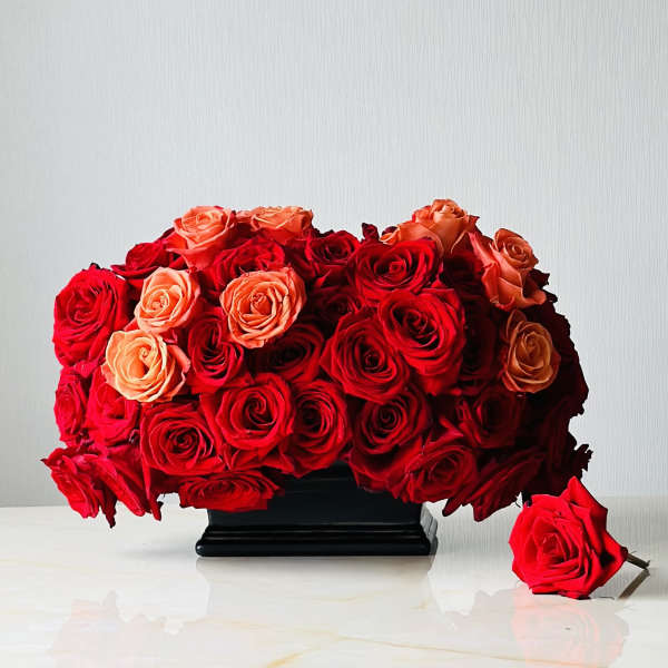 Red and peach roses arranged in a black vase