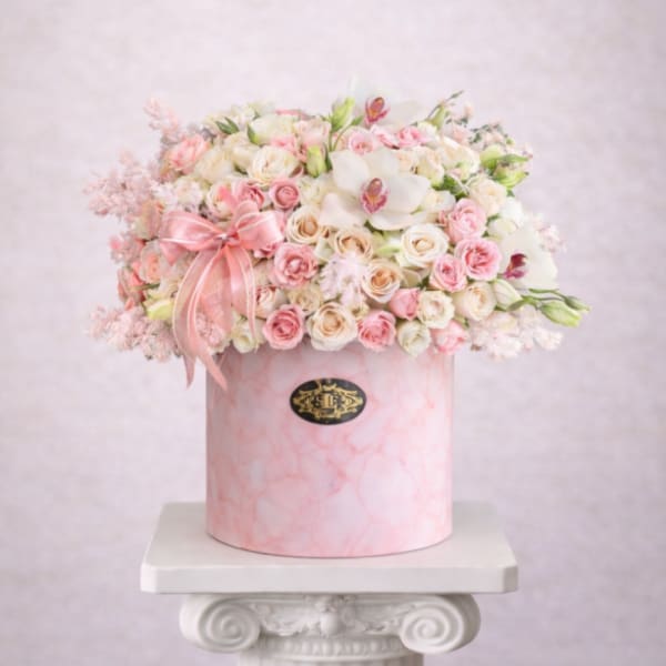 Pink and white rose arrangement in a round pink box with a ribbon