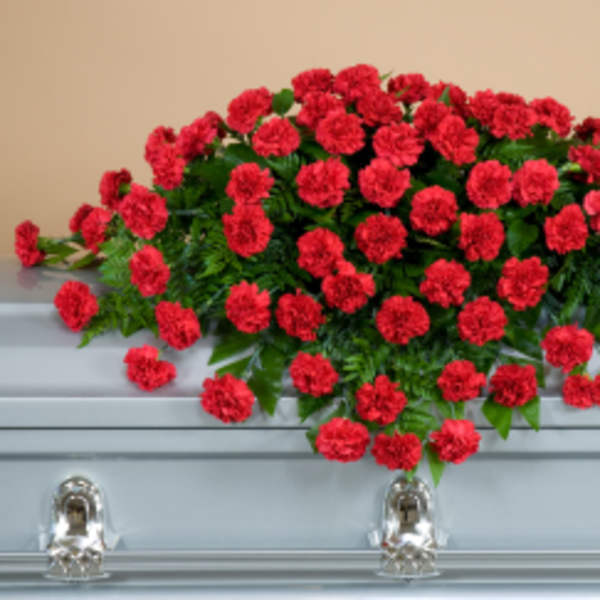 Red carnation spray arranged on a silver casket