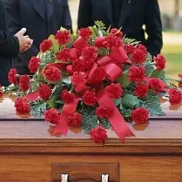 Red floral spray on top of a wooden casket