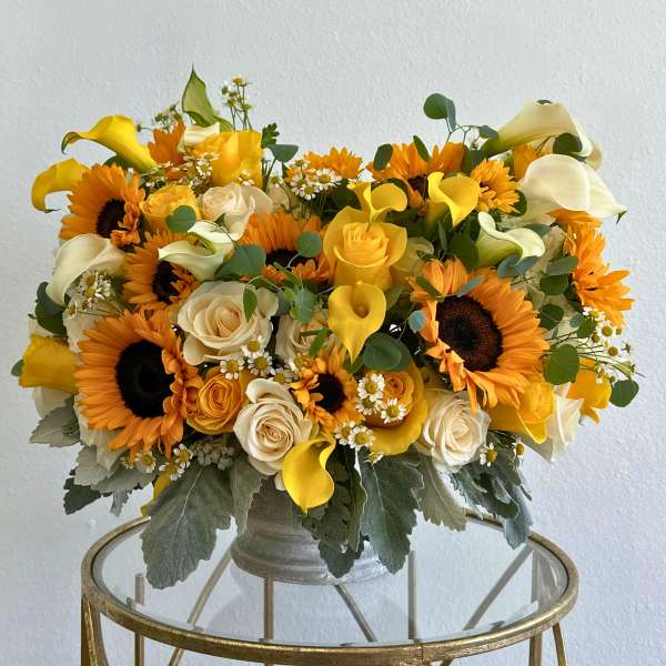 Bouquet of sunflowers, yellow roses, and white calla lilies in a vase