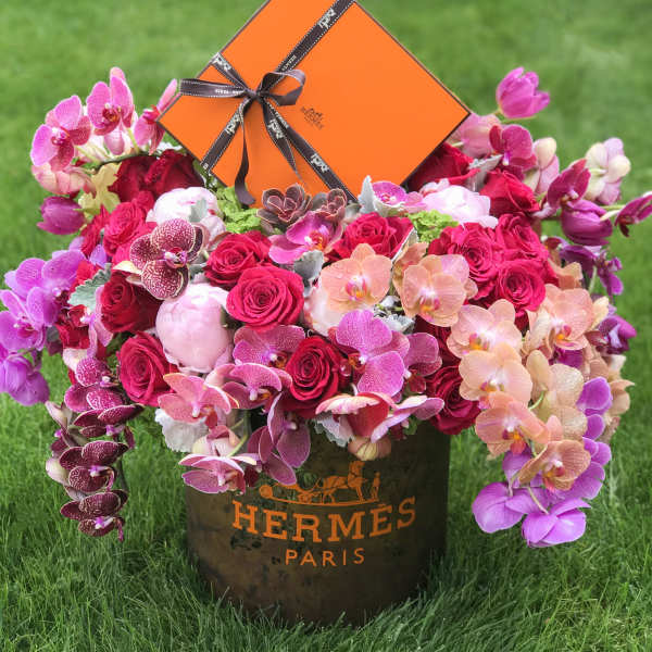 Pink and red floral arrangement in a Hermes Paris box with an orange gift box on top