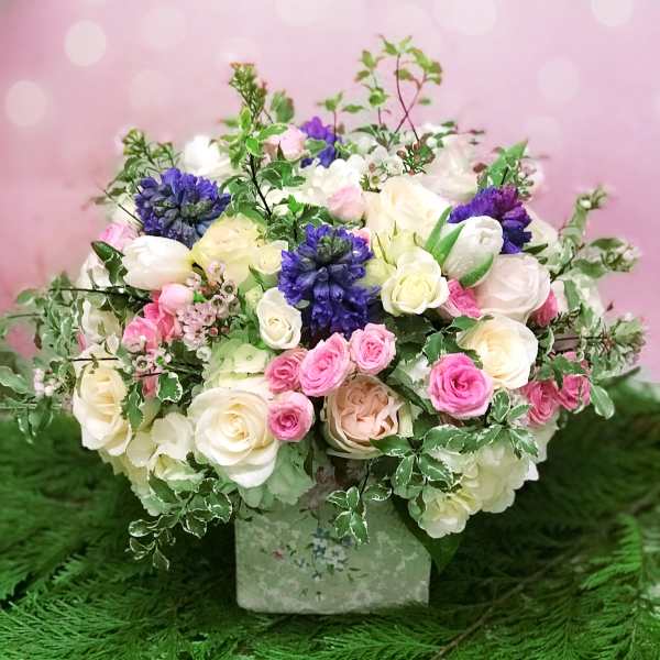 Mixed bouquet of pink, white, and purple flowers in a square box
