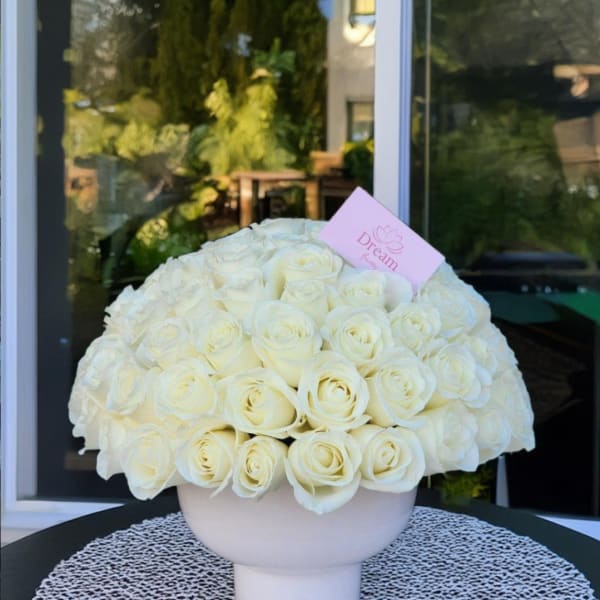 Large bouquet of white roses in a pale pink vase