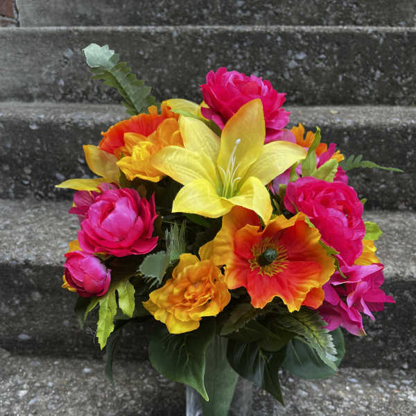 Bright mixed bouquet in a clear glass vase with pink, yellow, and orange blooms.