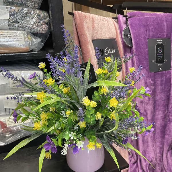Purple and yellow floral arrangement in a lavender vase