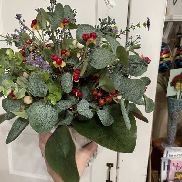 Handheld bouquet with eucalyptus, berries, and small purple accents