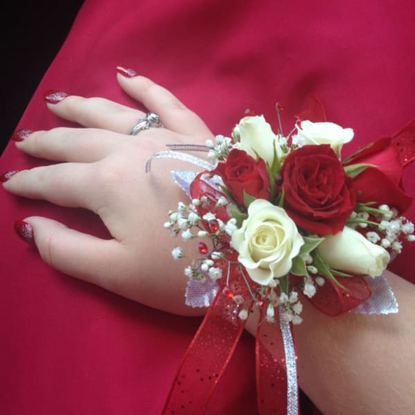 Red and white rose wrist corsage on a hand