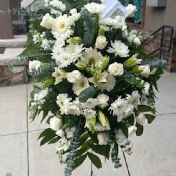 White funeral spray with lilies and daisies on a stand