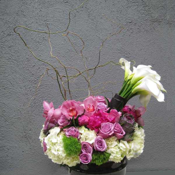Pink and white floral arrangement in a black pedestal vase