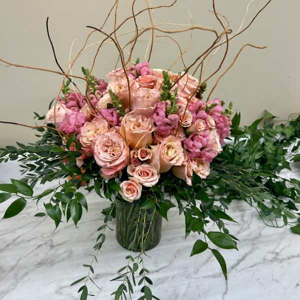 Pink roses and snapdragons in a glass vase with curly branches