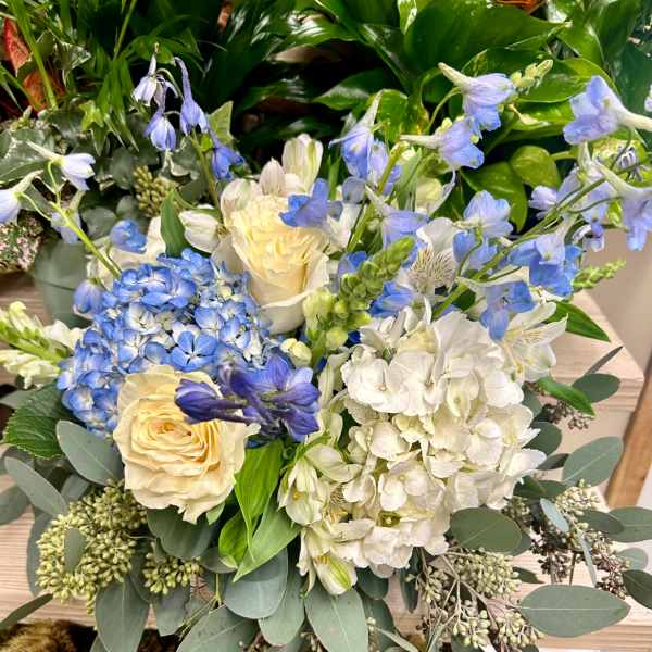 Blue and white floral arrangement with roses, hydrangeas, and delphinium