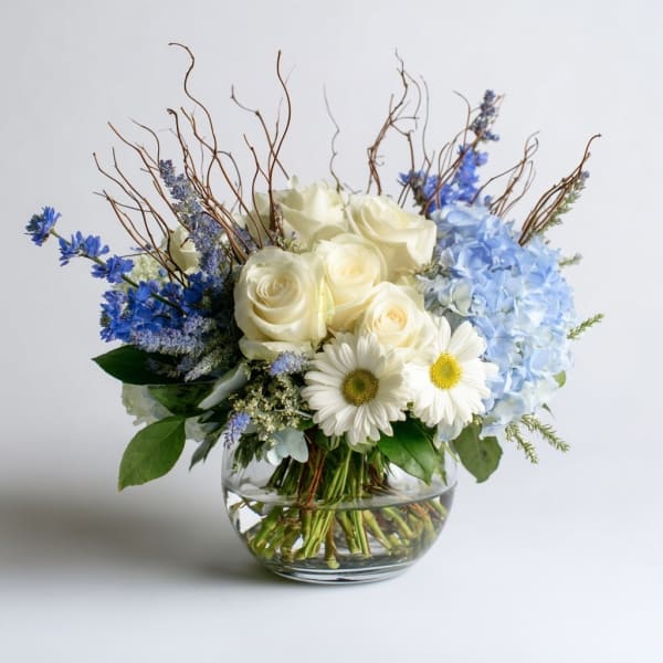 White roses and blue flowers in a clear glass vase
