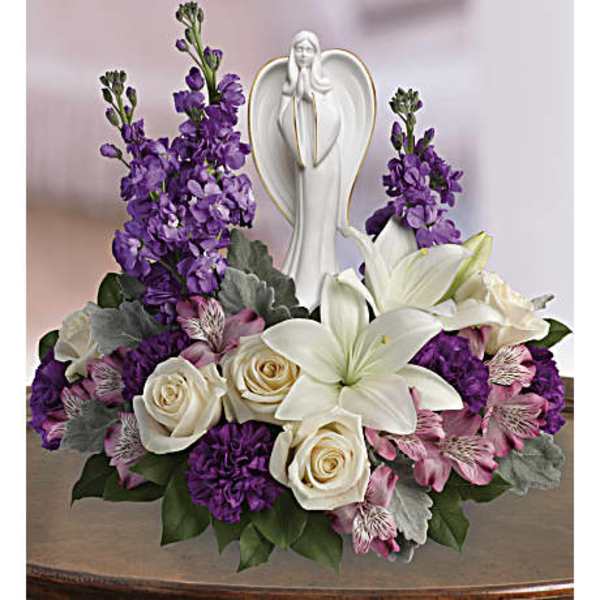 Purple and white floral arrangement with a praying angel figurine