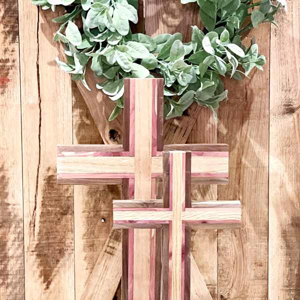 Wooden cross display with green foliage on a rustic wood backdrop