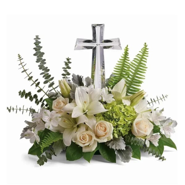 White lilies and roses arranged around a clear glass cross