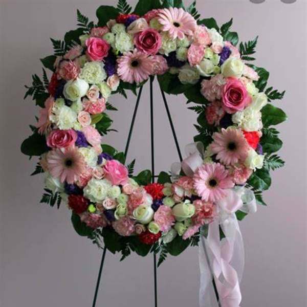 Heart-shaped floral wreath on a stand with pink and white flowers