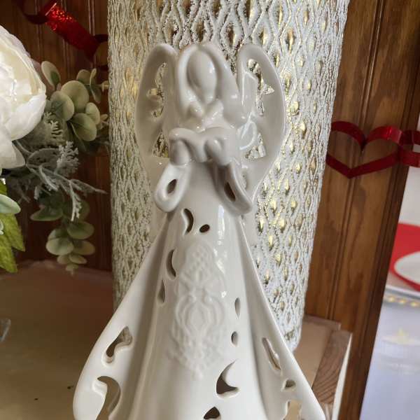 Ceramic angel figurine with cutout details on a shelf