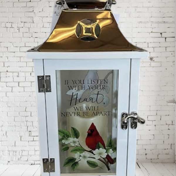 White lantern with a cardinal and floral design on the glass door