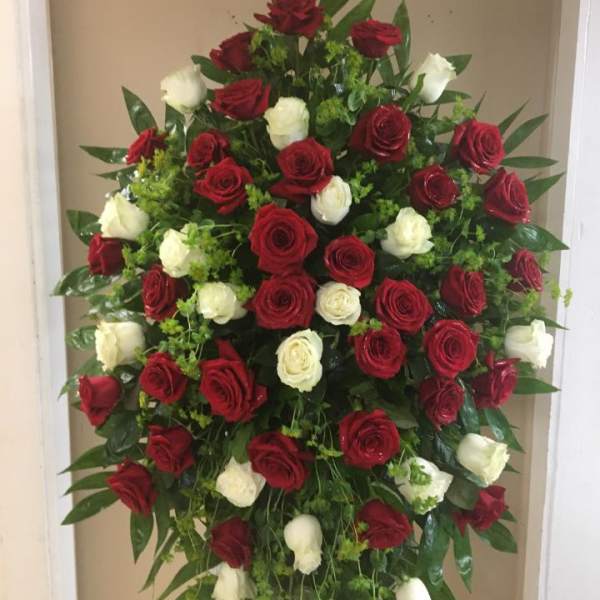Standing spray of red and white roses with greenery