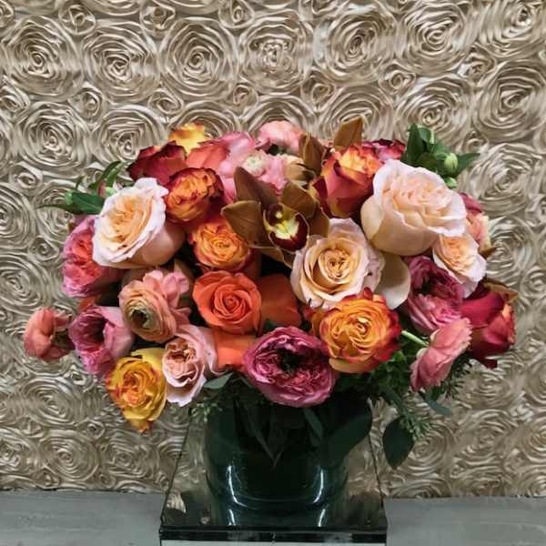 Mixed roses in a dark vase against a textured wall