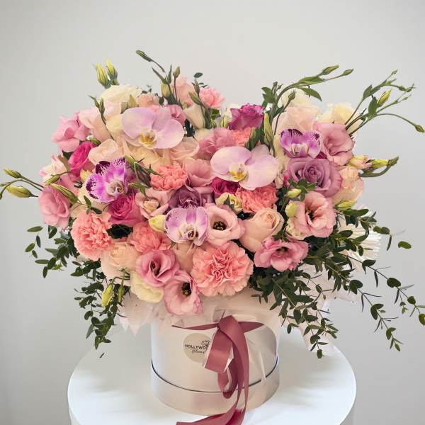 Pink and cream flower arrangement in a round hat box with ribbon