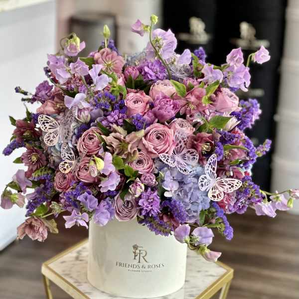 Lavender and pink bouquet in a white vase with butterfly accents
