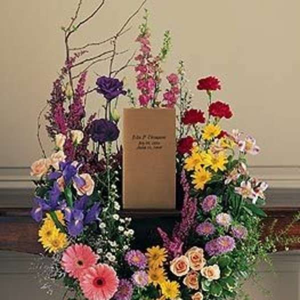 Large floral wreath with mixed colorful flowers around a central sign