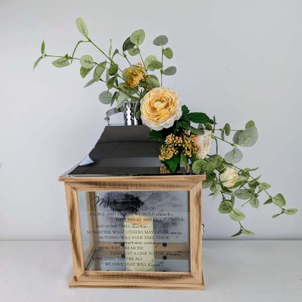 Floral arrangement with cream roses and eucalyptus in a wooden memorial lantern