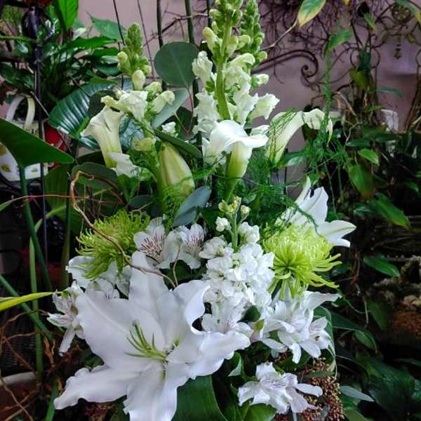 White lilies and snapdragons arranged in a glass vase