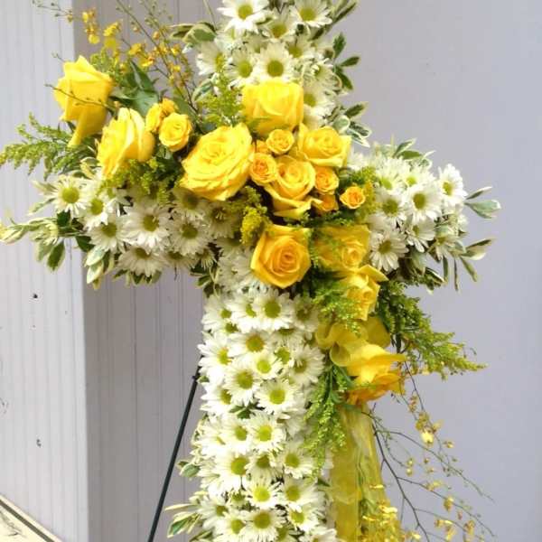 Yellow roses and white daisies arranged in a cross-shaped floral tribute