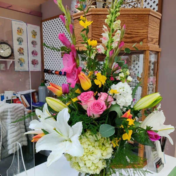 Tall mixed bouquet with lilies, roses, hydrangea, and snapdragons in a glass vase
