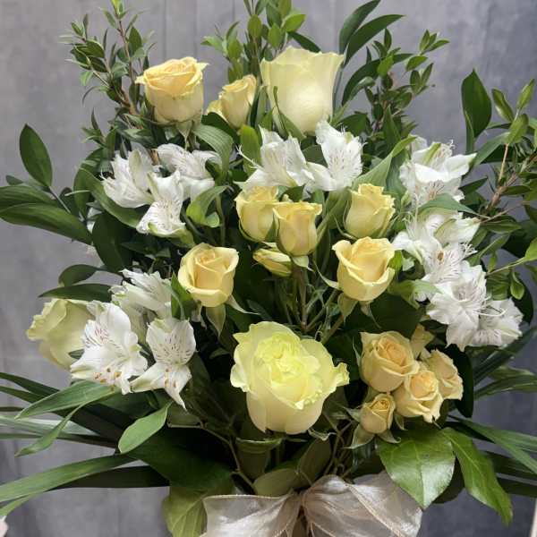 Bouquet of pale yellow roses and white alstroemeria in a glass vase