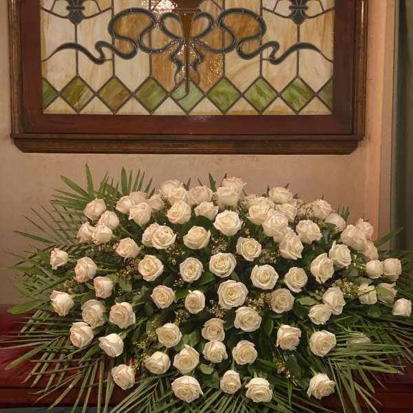 Large white rose arrangement with palm fronds on a stand
