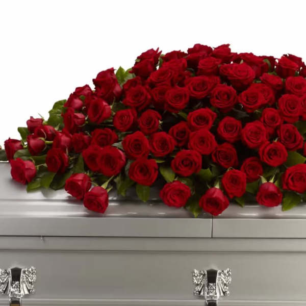 Large spray of red roses on a white casket