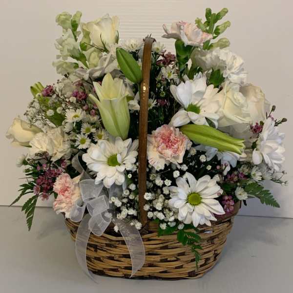 Basket arrangement of white flowers with pink accents and a ribbon bow