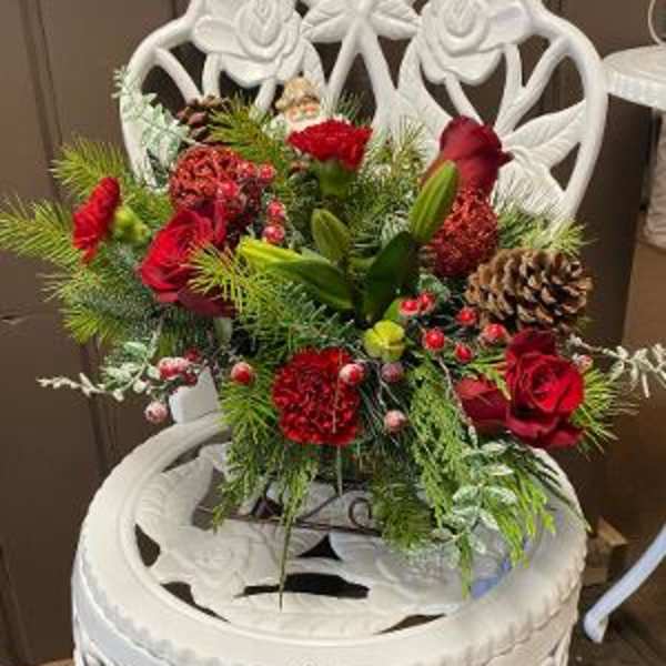Red floral arrangement with pinecones in a white decorative chair