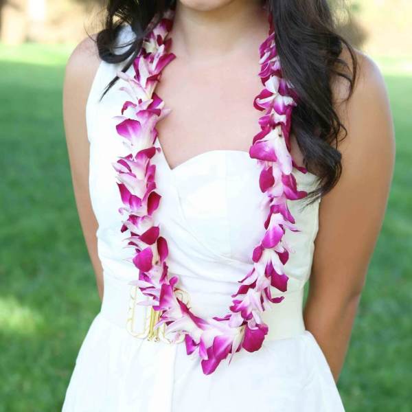 Woman wearing a pink and white orchid lei over a white dress